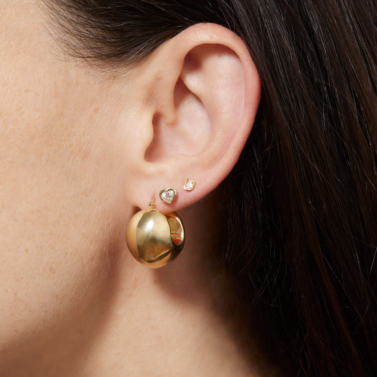 Model wearing Ultra Puff Gold Huggies with solid gold Stone and Strand jewelry