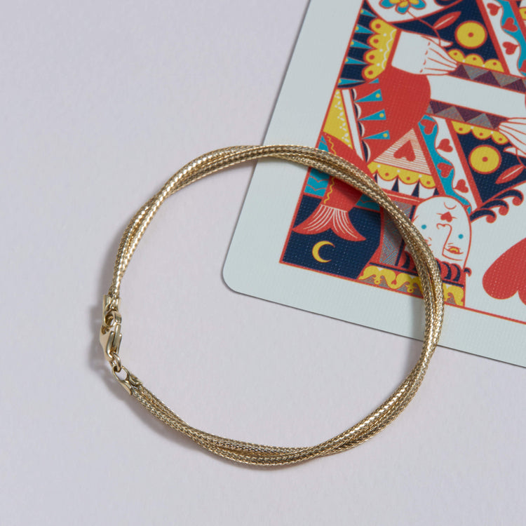 Still Life Image of 14K Yellow Gold Interwoven Gold Bracelet with Stone and Strand Bracelets