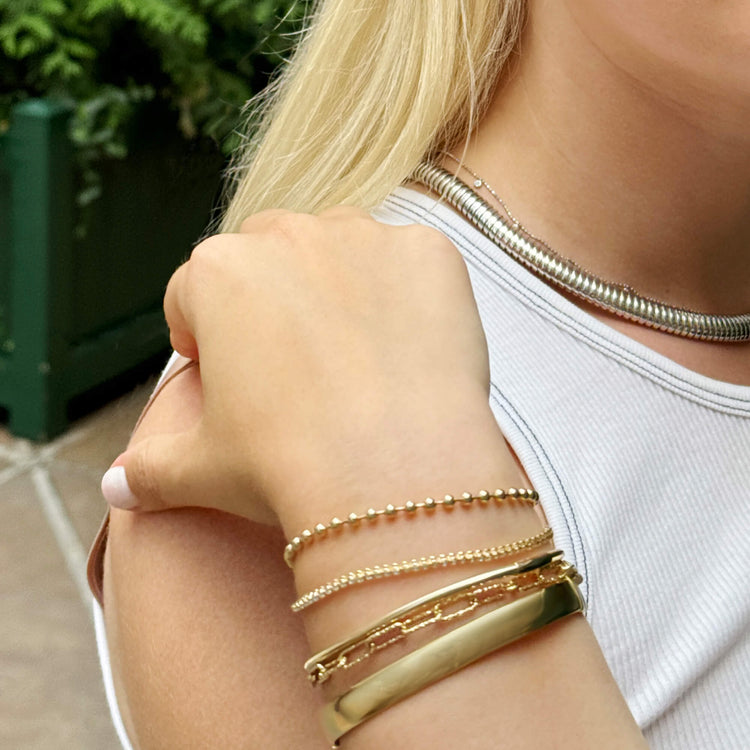 Model wearing Gold Cigar Bangle with solid gold Stone and Strand jewelry