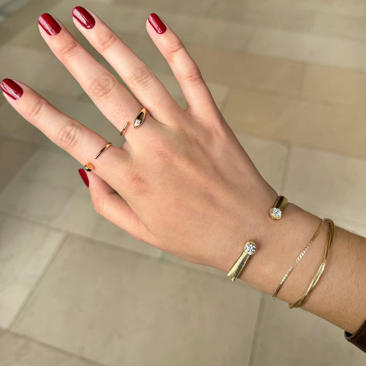 Model wearing Interwoven Gold Bracelet with solid gold Stone and Strand jewelry