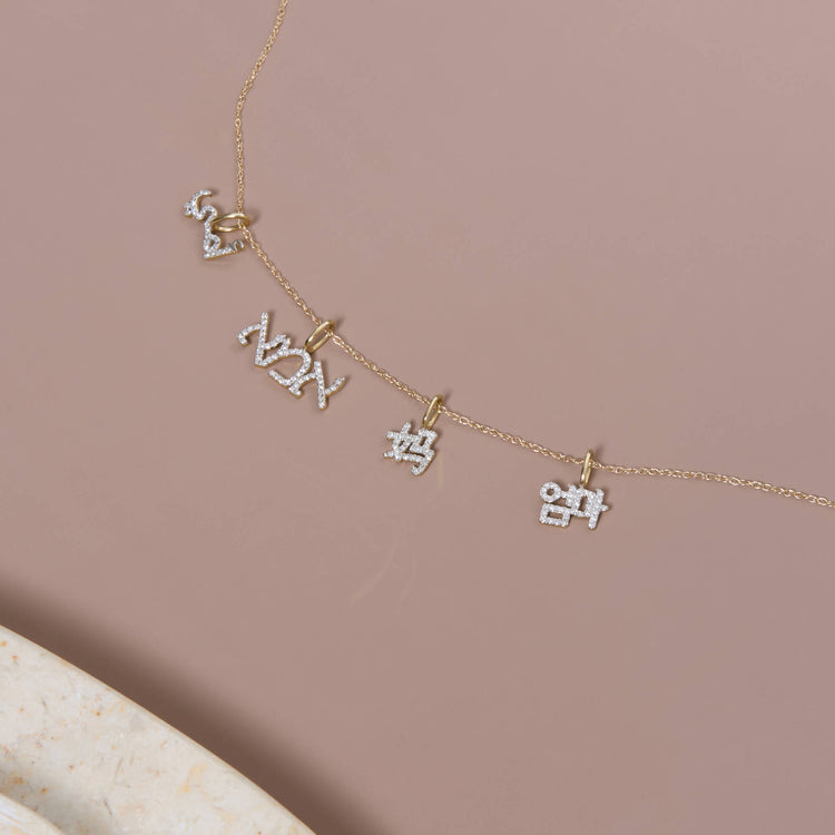 Still life image of Arabic Mother's Day Charm with Stone and Strand solid gold jewelry