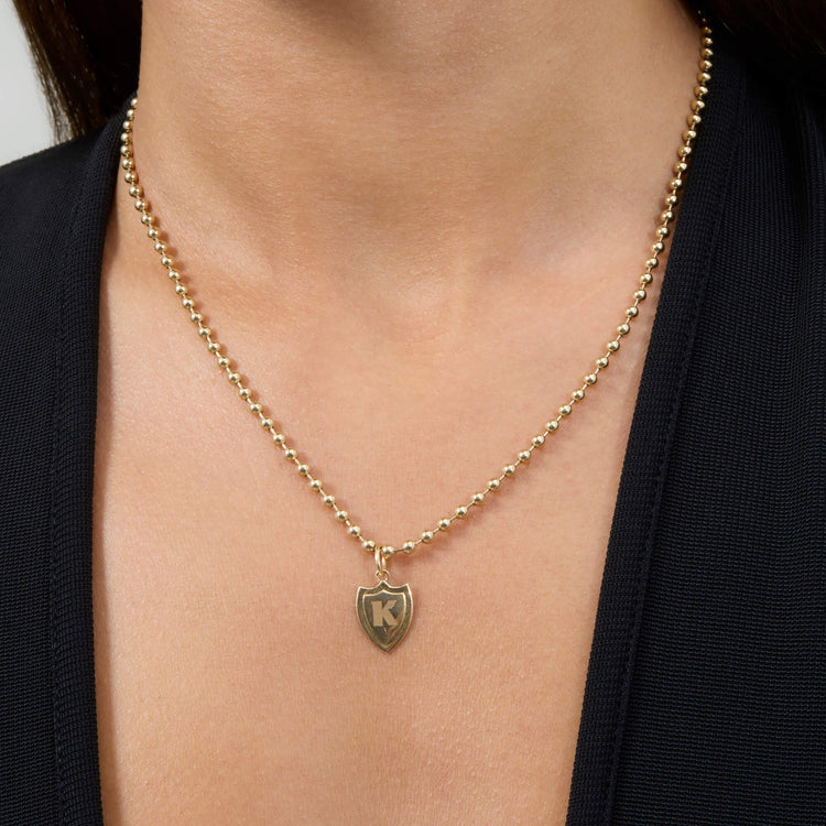 Image of 14K Yellow Gold Small Gold Initial Crest Charm on Models Neck