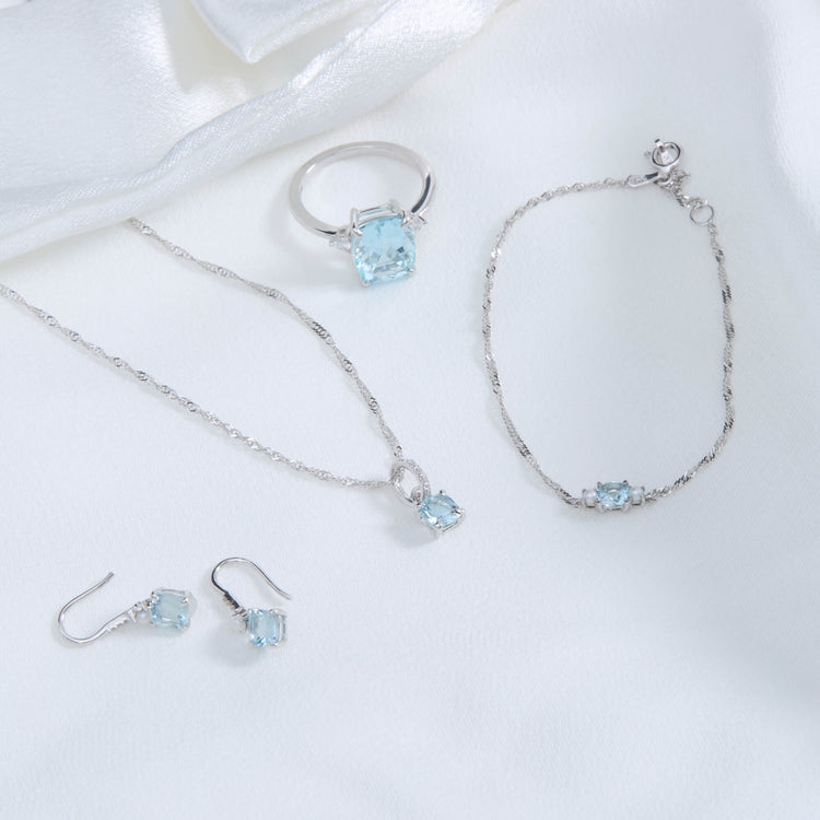 Still life image of Cushion Cut Aquamarine and Pearl Drop Earrings with Stone and Strand solid gold jewelry