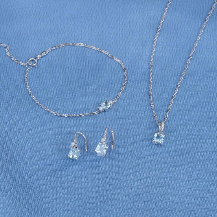 Still life image of Cushion Cut Aquamarine and Pearl Drop Earrings with Stone and Strand solid gold jewelry