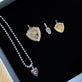 Still life image of Founding Member Diamond Crest Charm with Stone and Strand solid gold jewelry