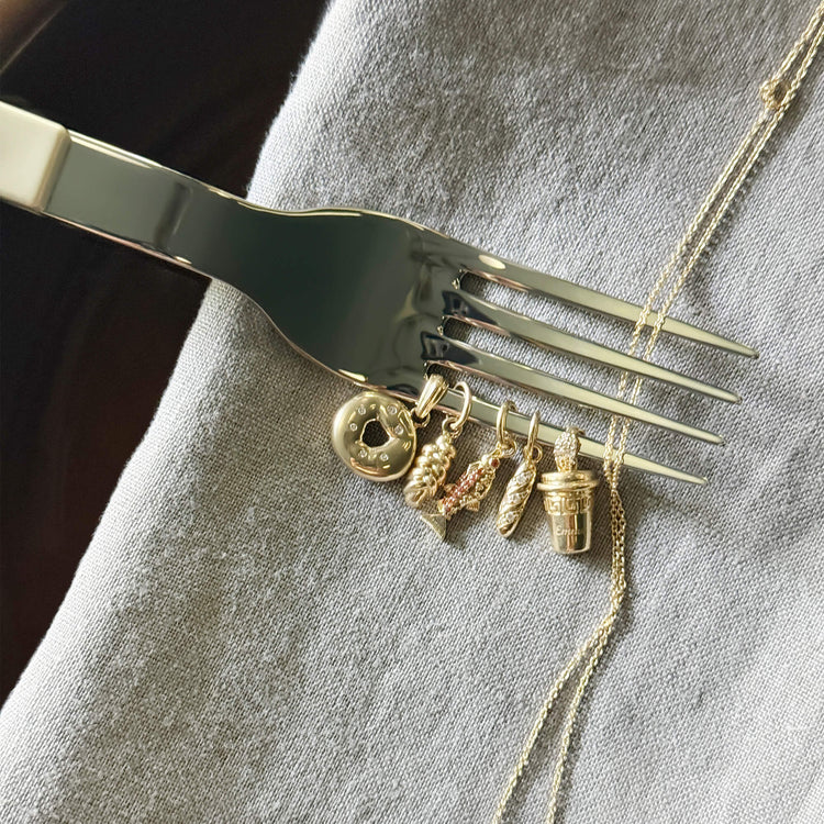 Still life image of Gold Salmon Charm with Stone and Strand solid gold jewelry