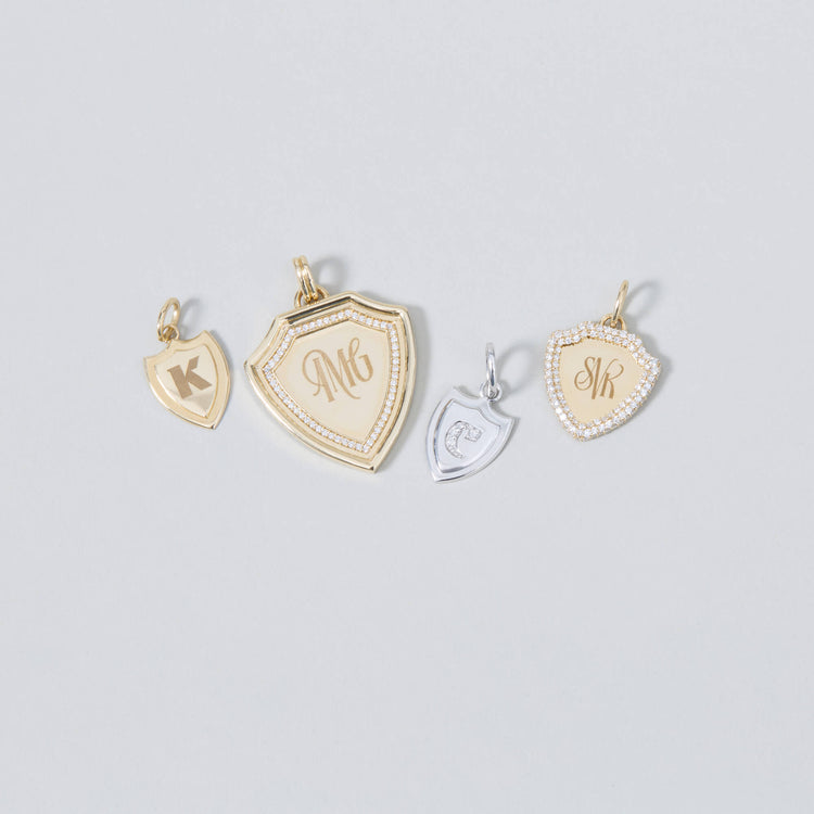 Still life image of Small Gold Initial Crest Charm with Stone and Strand solid gold jewelry