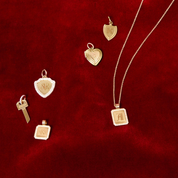 Still life image of Small Gold Initial Crest Charm with Stone and Strand solid gold jewelry