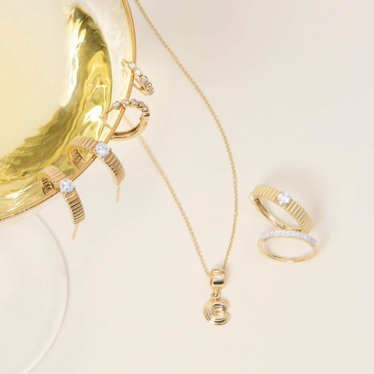 Still life image of Puffed Initial Charm with Stone and Strand solid gold jewelry