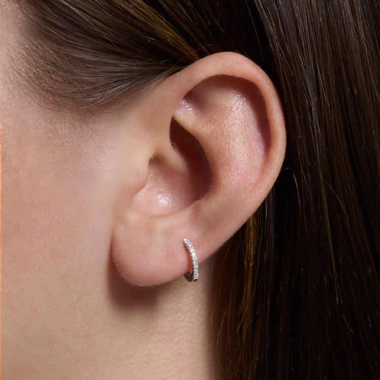 Image of 10K White Gold Dainty White Diamond Pave Huggie Earrings on Models Ear