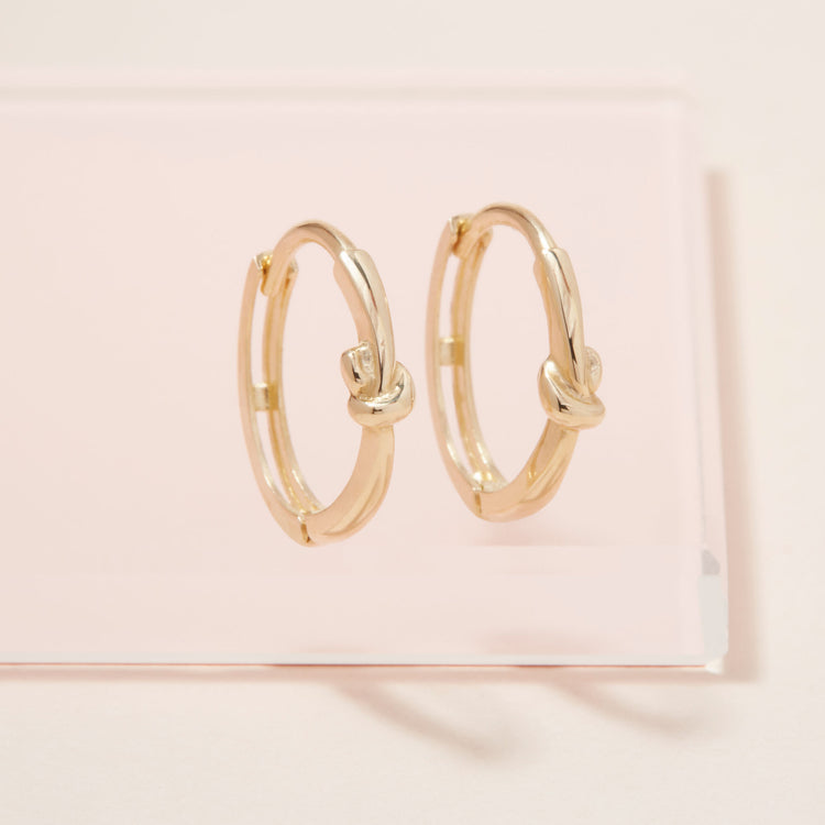 Stone and Strand 10K Yellow Gold Gold Knot Huggies Editorial Image