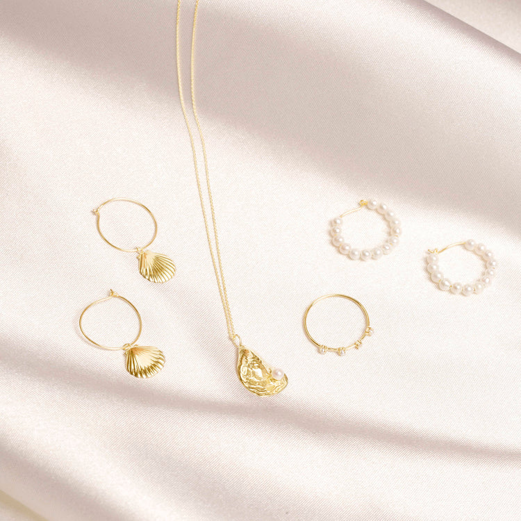 Still life image of Pearly Huggies with Stone and Strand solid gold jewelry